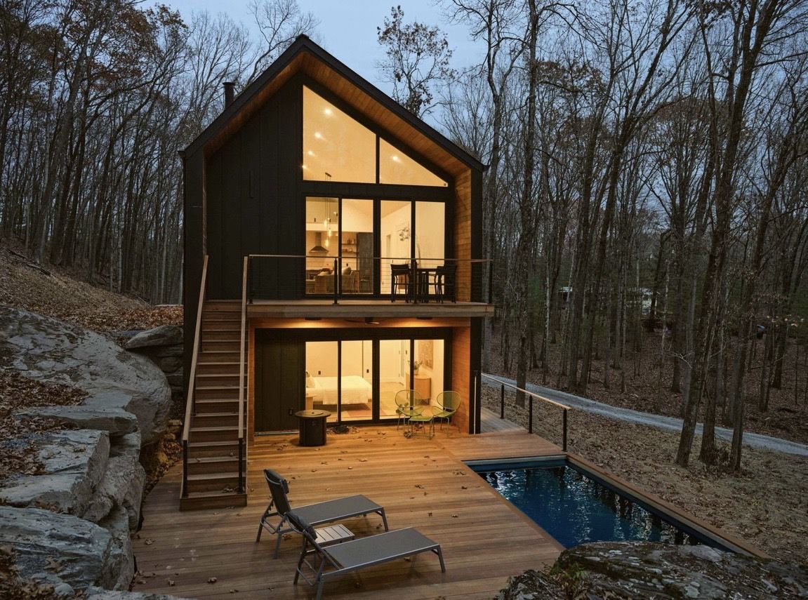 Oak Ridge exterior at dusk, lit from within, with pool and deck