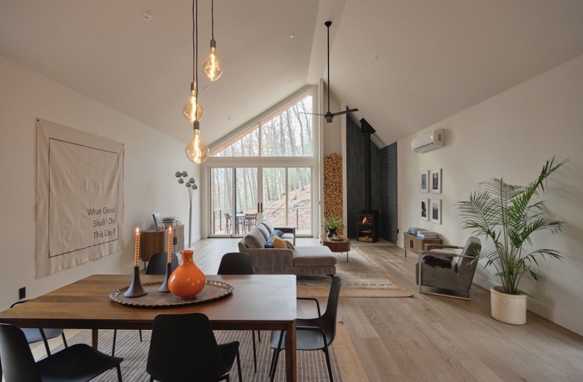 Living room with dining table, wood stove, and tall windows