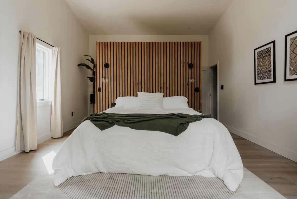 Bedroom with a wood slat headboard wall and olive throw