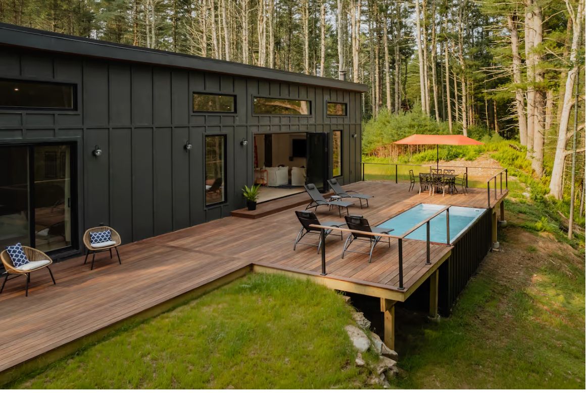 White Pines exterior with deck, pool, and red umbrella